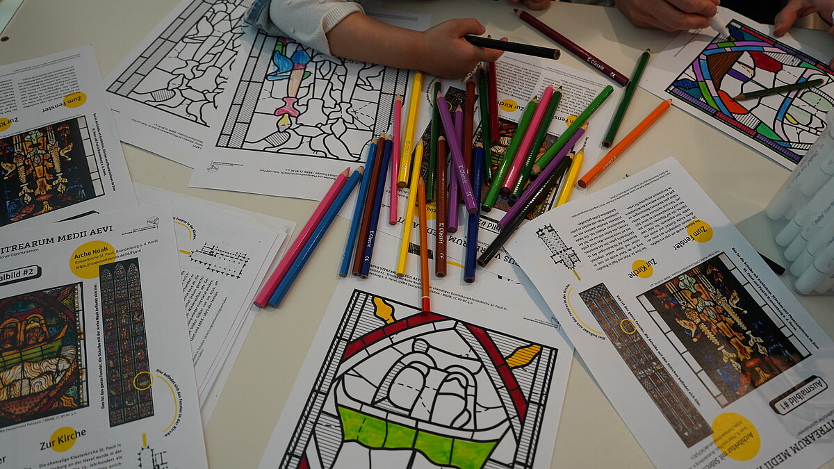 Kinder malen an einem Tisch Bilder von Glasfenstern aus