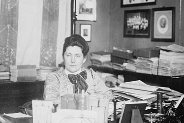 Lydia Rabinowitsch-Kempner sitzt in einem Büro voller Zettel, Hefter und Blöcke.