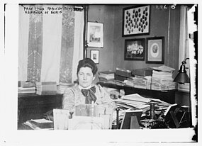 Lydia Rabinowitsch-Kempner sitzt in einem Büro voller Zettel, Hefter und Blöcke.