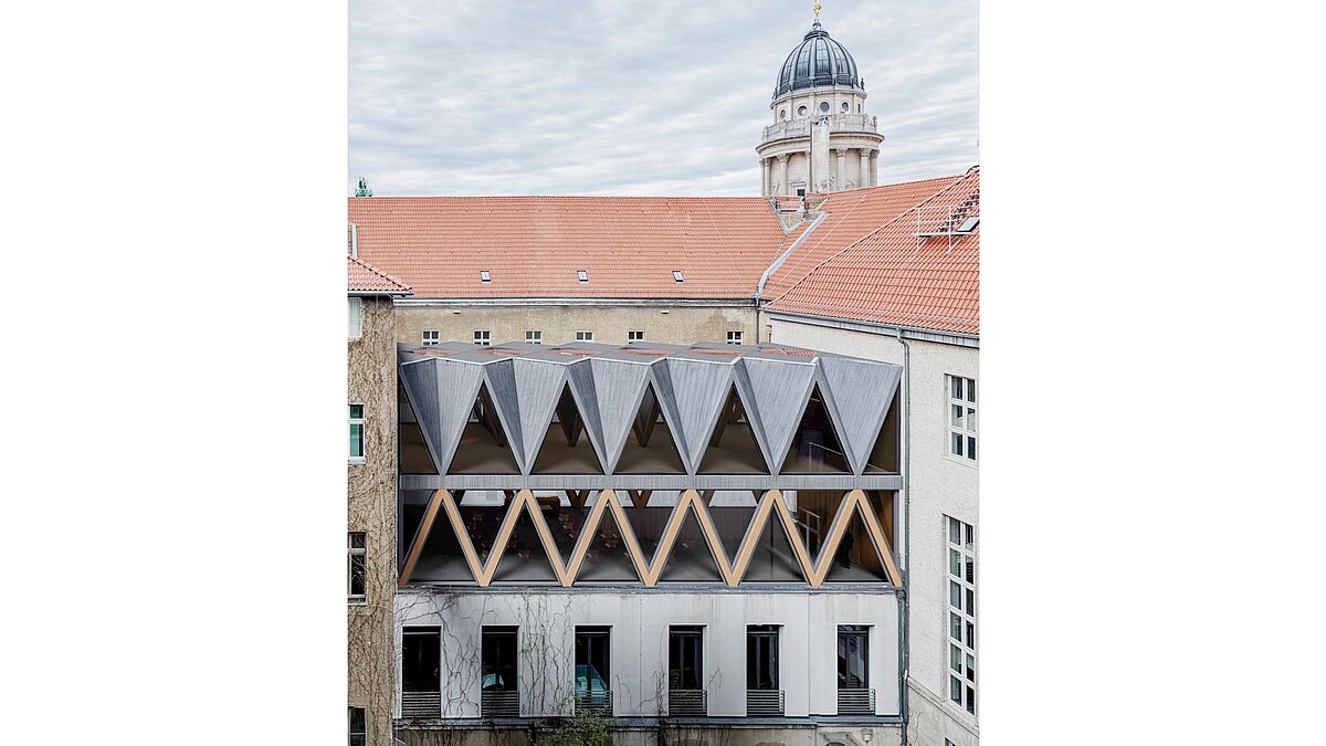 Außenansicht der geplanten Wissenschaftslounge mit hölzernen Dreiecken vor gläserner Fassade