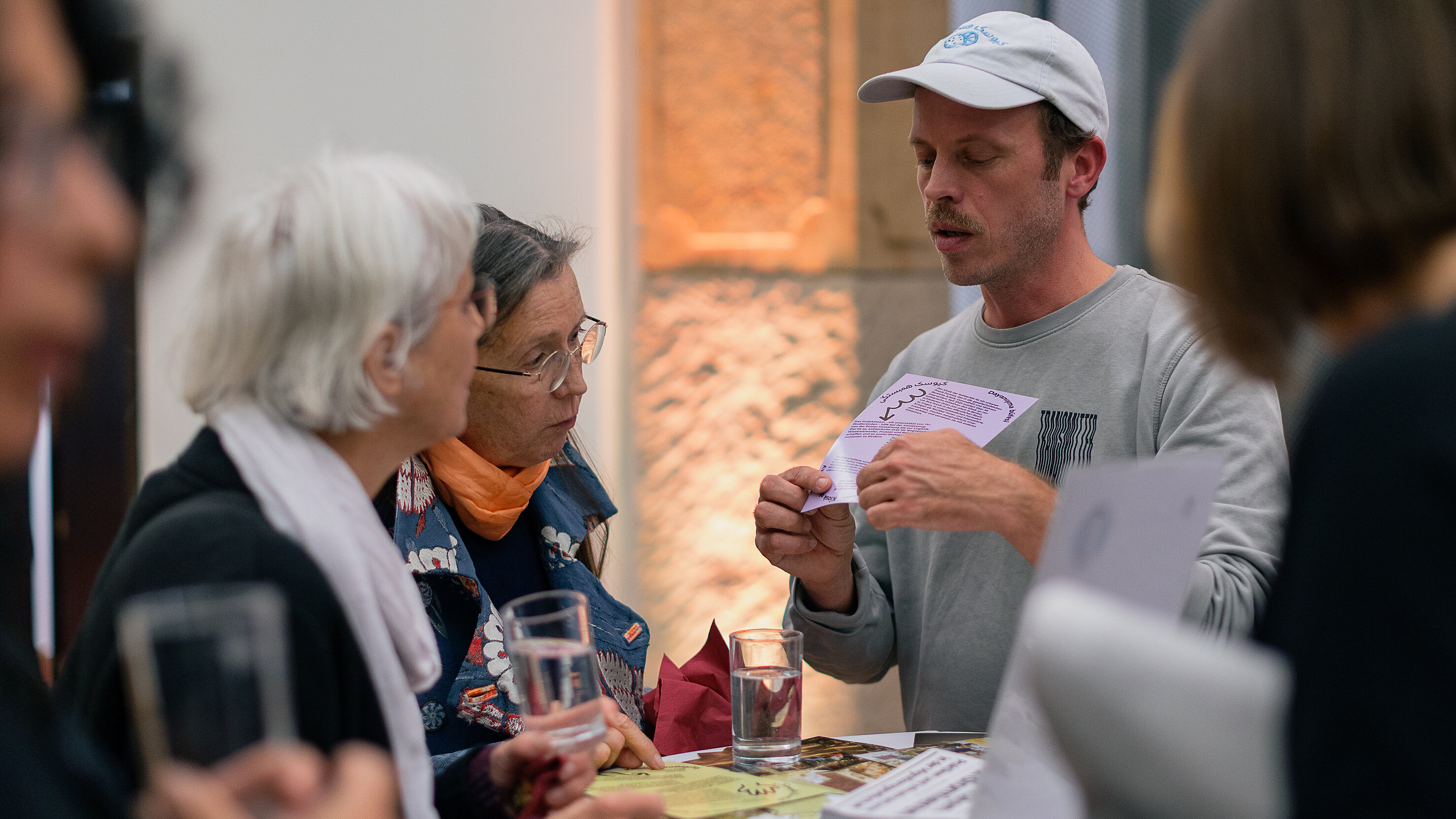 Foto von einem jungen Mann, der zwei Frauen ein Diagramm auf dem "Kiosk der Solidaität steht" zeigt
